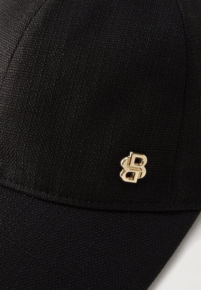 Gorra de béisbol negra con textura y un pequeño pin brillante dorado con el logo doble "B" fijado cerca del panel central delantero.