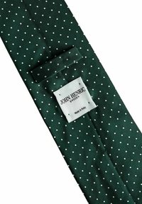 Tumma vihreä silkkisolmio, jossa on valkoisia pilkkuja, takana on "John Henric Sweden" -merkki ommeltuna.