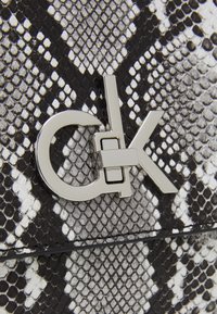Borsa con motivo in pelle di serpente, in bianco e nero, dotata di una chiusura in metallo argentato con lettere intrecciate "C" e "K". Texture liscia.