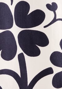 Stoff mit großen dunkelblauen Blüten mit herzförmigen Blütenblättern auf einem hellen Hintergrund. Glatte Textur mit einem kühnen grafischen Design.