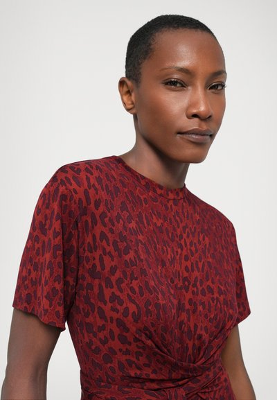 Rode jurk met een panterprint, korte mouwen en een geknoopt detail bij de taille. Soepele textuur en aansluitend ontwerp.