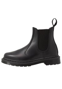 Botín Chelsea negro con cuero brillante y suave, paneles laterales elásticos y suela de goma plana, diseñado para el estilo y la comodidad.