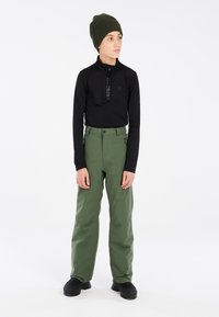 Černé dlouh�é rukávy s límcem na zip, zelené voděodolné kalhoty, černé boty a tmavě zelená pletená čepice. Jednoduchý a funkční design.
