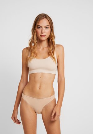 Beige geribde bralette en bijpassende thong, met zachte stof, minimalistisch ontwerp en een gladde textuur met dunne bandjes.