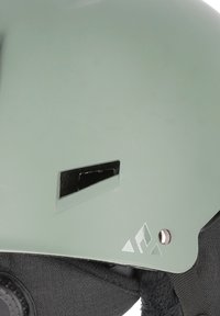 Grøn hjelm med mat finish, ventilationsåbning og justerbar sort polstring. Har en sølvaccent ved siden.