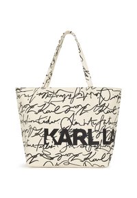 Bolsa de tela beige con texto negro escrito a mano y un prominente logo "KARL". El diseño incluye una forma espaciosa y estructurada con dos asas.