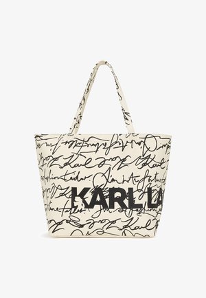 Beige fabric tote bag featuring black handwritten text and a prominent "KARL" logo. The design includes a spacious, structured shape and dual handles.