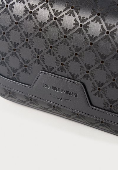 Μαύρο δέρμα με υφή, διακοσμημένο με διάτρητο γεωμετρικό μοτίβο και ανάγλυφο λογότυπο Emporio Armani Milano 1981 σε ραμμένη ετικέτα.