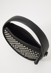 Black leather bag with a round shape, featuring a zipper closure and a front adorned with silver studs. Smooth texture with inner compartment.