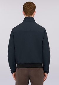 Giubbotto bomber blu navy con colletto alto, polsini e orlo a costine. Presenta un logo discreto sulla parte superiore della schiena e una texture liscia.