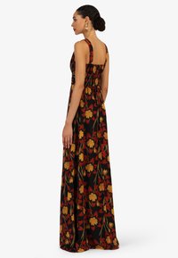 Maxikleid mit schwarzem Hintergrund und lebhaftem Blumenmuster in Gelb und Rot. Verfügt über ein tailliertes Oberteil mit Raffung und breiten Trägern.