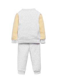 Sudadera de algodón gris con mangas amarillas y pantalones de chándal grises a juego. Presenta puños y dobladillo acanalados. Textura suave, ajuste casual.