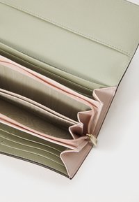 Groene gestructureerde portemonnee met een lichtroze interieur en meerdere compartimenten. Heeft een ritsvak en een gestructureerde afwerking.
