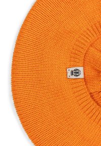 Bright orange knitted beret with a small white fabric tag featuring a black emblem stitched near the edge on a white background.