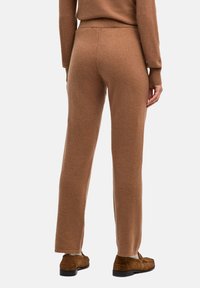 Brązowe spodnie z wysokim stanem wykonane z miękkiej, teksturowanej tkaniny o prostym kroju nogawki. Charakteryzują się dopasowaniem w talii i prążkowanym wykończeniem na dole.