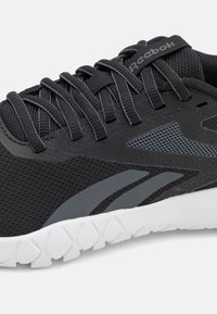 Sort sportsko med mesh-overdel og grå accenter, strukturerede overflader og en hvid gummisål med klart mønster.