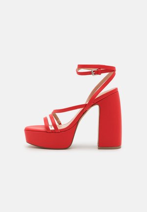 Red high-heeled sandals with three slim straps across the toe and ankle. Features a chunky platform and block heel for stability.