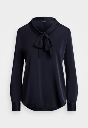 Marinebluse i glatt, satinaktig stoff med en sløyfedetalj ved kragen og lange ermer. Nederkanten er svakt buet.