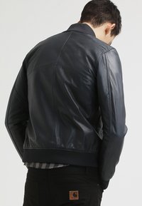 Svart läderbomberjacka med ribbad krage och ärmslut, med en slät yta och en åtsittande design. Bakvy utan synliga knäppningar.