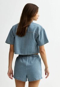 Kortärmad topp och matchande shorts i blå och vita vertikala ränder. Tillverkad av l�ättviktig material med elastisk midja.