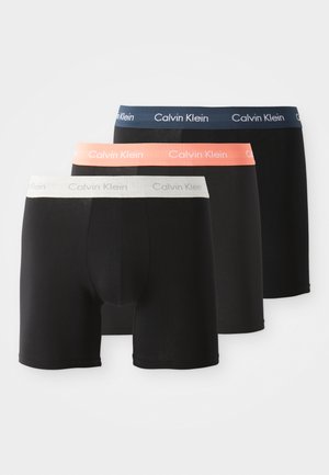 Czarne bokserki dla mężczyzn z elastycznymi pasami w kolorze granatowym, koralowym i białym. Materiał wydaje się miękki i gładki, z logo Calvina Kleina na pasach.