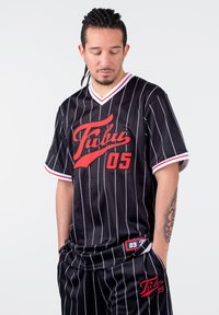 Juodos juostelės sportinė maikutė su raudonu logotipu "Fubu 05" priekyje. V-kaklo dizainas su baltais akcentais ant rankovių ir apykaklės.