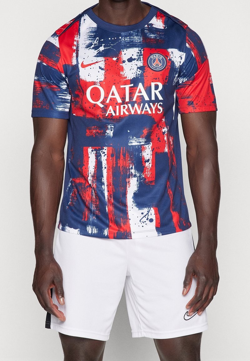 Fotbalový dres Nike má modrou základnu s červenými a bílými štětcovými vzory, logo na levé hrudi a design s kulatým výstřihem.