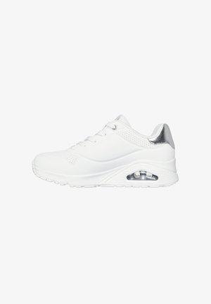 Zapatillas deportivas blancas con una parte superior sintética suave, un acento plateado en el talón, perforaciones de malla y una suela acolchada que presenta una unidad de aire visible.