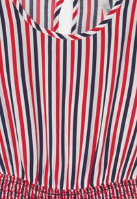 Sukienka bez rękawów w paski w kolorach czerwonym, białym i granatowym, z okrągłym dekoltem, marszczonym pasem i otworem w kształcie łezki z tyłu. Wykonana z bawełnianej tkaniny o gładkiej fakturze.