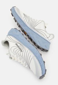 Weiße Laufschuhe mit einer blauen Zwischensohle, texturiertem Obermaterial mit schwarzen Linien und einer robusten schwarzen Außensohle für besseren Halt.