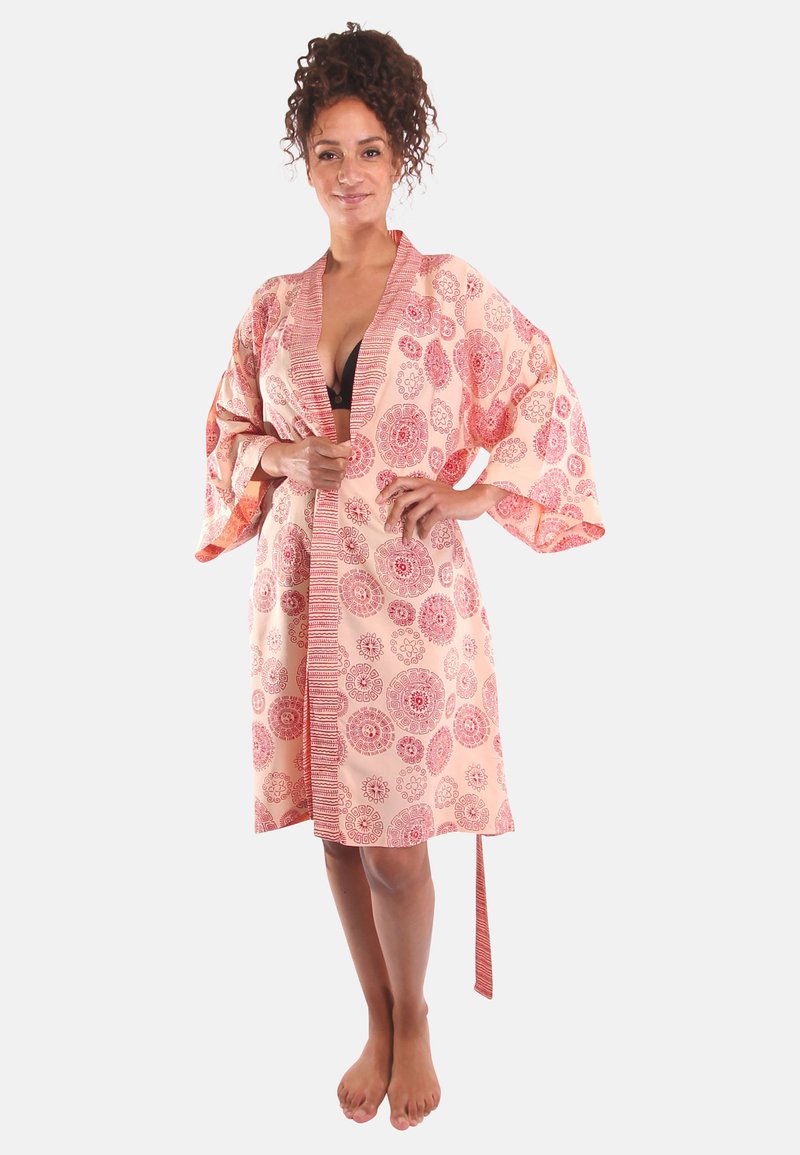 Kimono-achtige badjas van lichtroze stof met rode cirkelvormige patronen, brede mouwen, een strikceintuur en zijslits. Soepele textuur, casual ontwerp.
