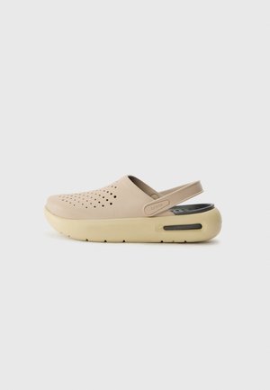 Beiger Slip-On-Clog mit Belüftungslöchern oben, verstellbarem Fersenriemen und dicker, gepolsterter cremefarbener Sohle mit schwarzen Akzenten.