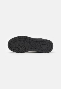 Suela de zapato de goma negra con un patrón texturizado que presenta surcos y un acento circular, diseñado para ofrecer agarre y durabilidad.
