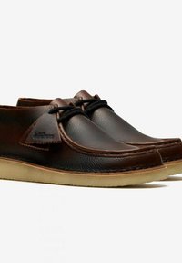 Scarpe in pelle marrone con punta rotonda, design con lacci e suola in gomma crepe. Presentano accenti cuciti e un'etichetta in pelle con marchio.