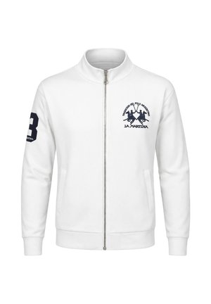 Giacca bianca con zip e colletto alto, con logo del giocatore di polo blu navy sul petto e numero 3 sulla manica destra.