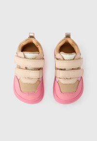 Παπούτσια για νήπια με ροζ σόλες και μπεζ επάνω μέρος, που διαθέτουν δύο ρυθμιζόμενους ιμάντες βέλκρο σε κάθε παπούτσι, απεικονισμένα σε λευκό φόντο.