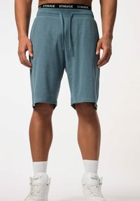 Turquoise shorts met een elastische tailleband, voorzien van een zwart "STHUGE" logo en twee zijzakken. Zachte, textuurstof, knie-lange ontwerp.