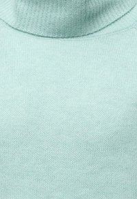 Gros plan d'un pull à col roulé tricoté bleu clair montrant le col côtelé et la texture lisse du tissu tricoté.