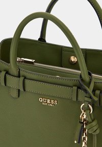 Bolso de mano verde de cuero con diseño estructurado, doble asa, herrajes dorados, cierre de cremallera y marca grabada en la parte frontal.