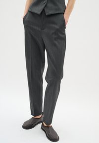 Grå veckade byxor i ett slätt tyg, med en tapered bendesign och sidofickor. Kombinerade med eleganta bruna slip-on skor.