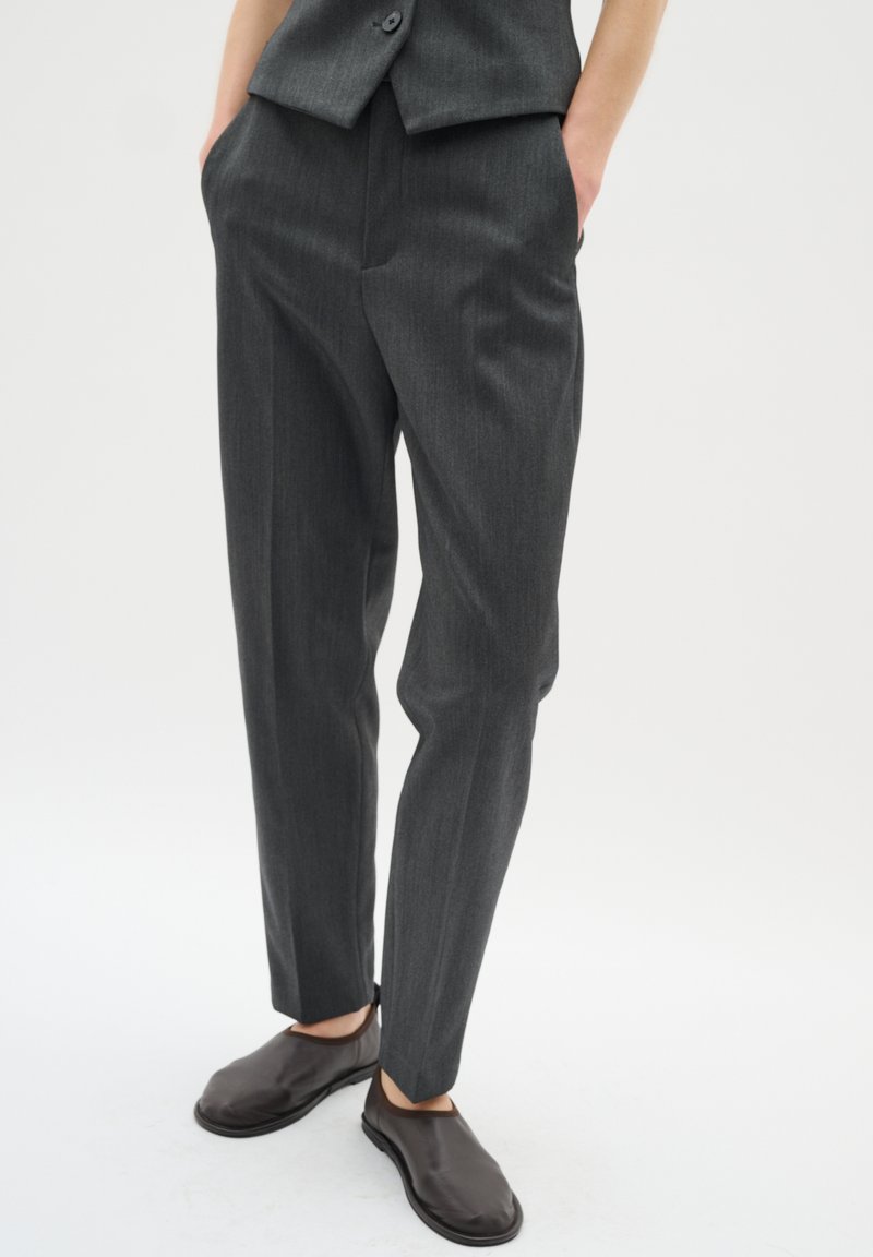 Grå veckade byxor i ett slätt tyg, med en tapered bendesign och sidofickor. Kombinerade med eleganta bruna slip-on skor.
