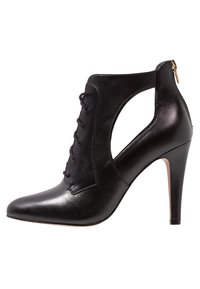 Musta nahkainen nilkkurit kärjellä, nauhallisella edessä, sivuissa leikkaukset ja piikkikorko. Takana vetoketju sulkemista varten.