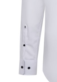 Weißes Langarmhemd mit Knopfmanschette. Verfügt über schwarze Knöpfe und ein kleines schwarzes Blumenemblem nahe der Manschette. Glatter, einfarbiger Stoff.