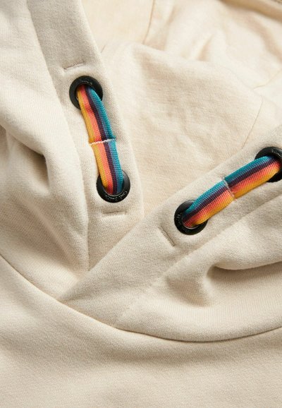 Felpa con cappuccio color beige chiaro in tessuto dalla finitura texturizzata. Presenta occhielli neri e cordini multicolori con strisce blu, arancioni e gialle.