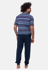 Gestreept T-shirt in marineblauw met lichtblauwe en bordeauxrode strepen, gecombineerd met marineblauwe broeken. Zachte stof, relaxte pasvorm, korte mouwen, elastische manchetten.