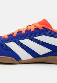Blue athletic shoe featuring lightweight mesh upper, orange laces, and white stripes. Cushioned sole with a tan rubber outsole.