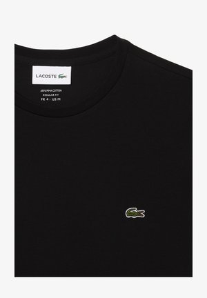 Camiseta negra hecha de 100% algodón Pima, con un cuello redondo clásico, ajuste regular y un pequeño logo de cocodrilo verde bordado.