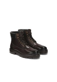 Botine din piele maro, cu vârful rotunjit, găici aurii, accente negre și talpă rugged pentru aderență. Textură netedă și detalii cusute.