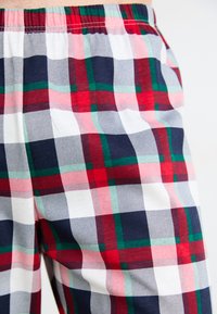 Pantaloni del pigiama a quadri in cotone, con un motivo rosso, verde, bianco e blu navy. Vita elastica con tessuto leggero e strutturato.