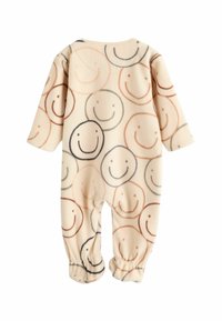 Fleece-Einteiler in Creme mit einem durchgehenden Muster aus lächelnden Gesichtern in Brauntönen und Schwarz; verfügt über elastische Bündchen für einen engen Sitz.